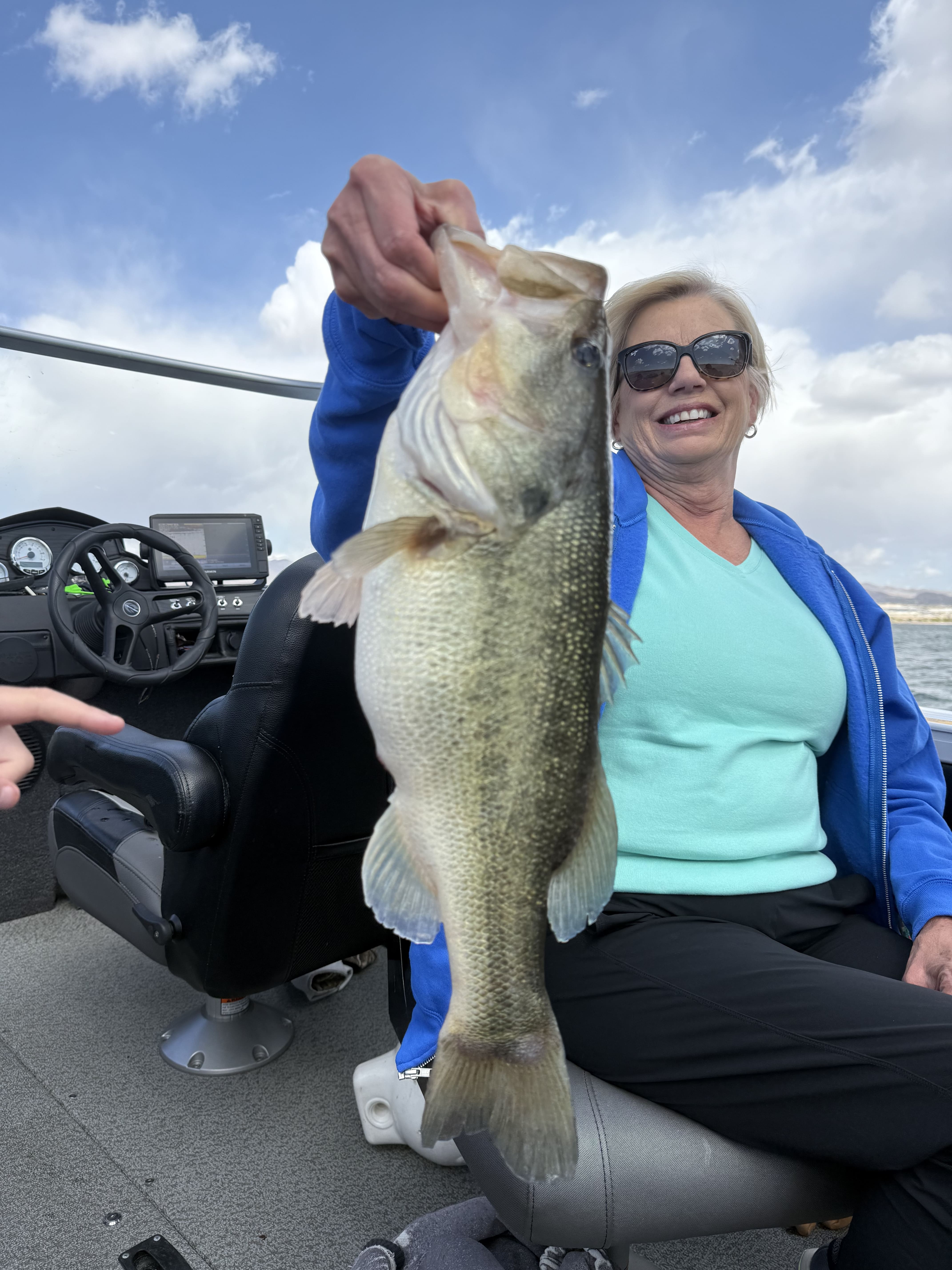 Angler smiling and holding a largemouth bass from the boat