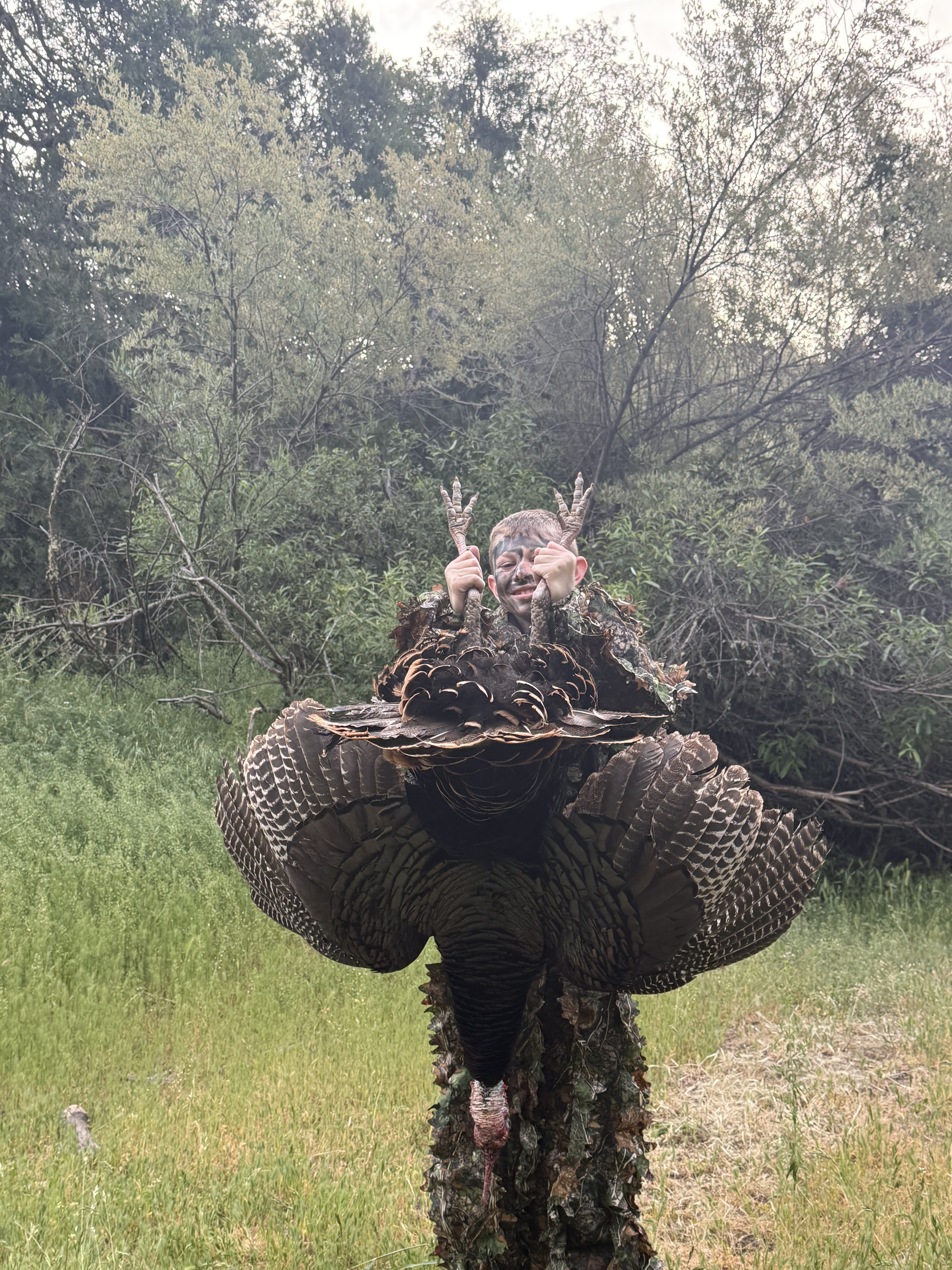Young hunter holding a turkey in camouflage