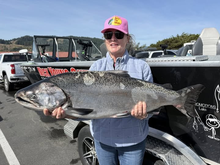 Angler holding a Chinook salmon at the dock beside the guide boat
